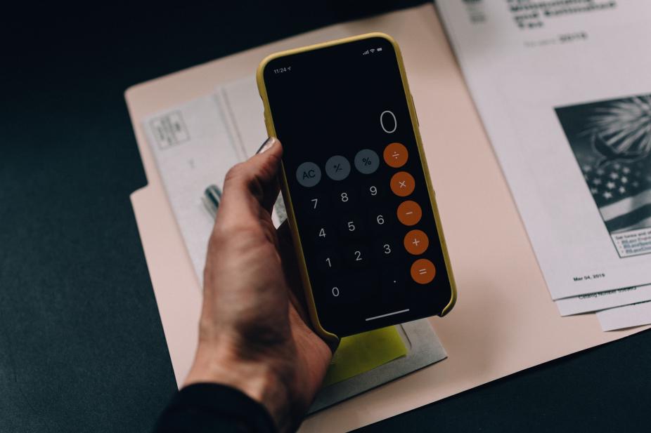 A hand holding a calculator with the display as number 0.