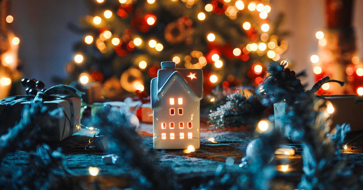 Illuminated holiday decorations with Christmas tree lights and decorative house lantern, representing winter energy costs and holiday electricity use